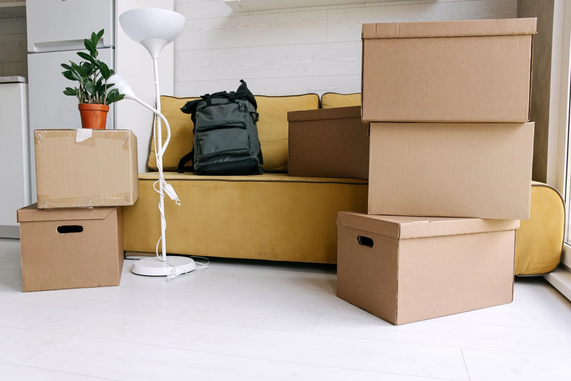 Canapé jaune, cartons de déménagement et sac à dos prêts avant un départ à l'étranger